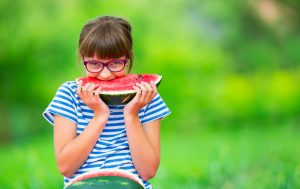 Child eating watermelon. Kids eat fruits in the garden. Pre teen girl in the garden holding a slice of water melon. happy girl kid eating watermelon.